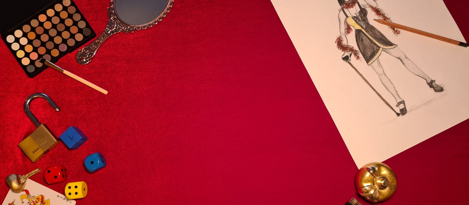 Palette de maquillage, miroir ancien, cadenas et croquis de costume sur un tissu rouge