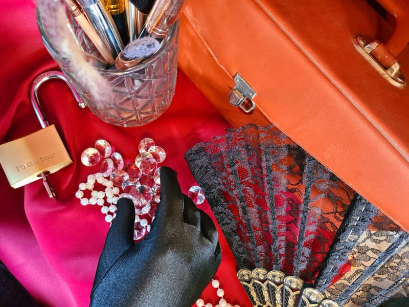 Accessoires du jeu : éventail, bijoux et boîte rouge sur une table