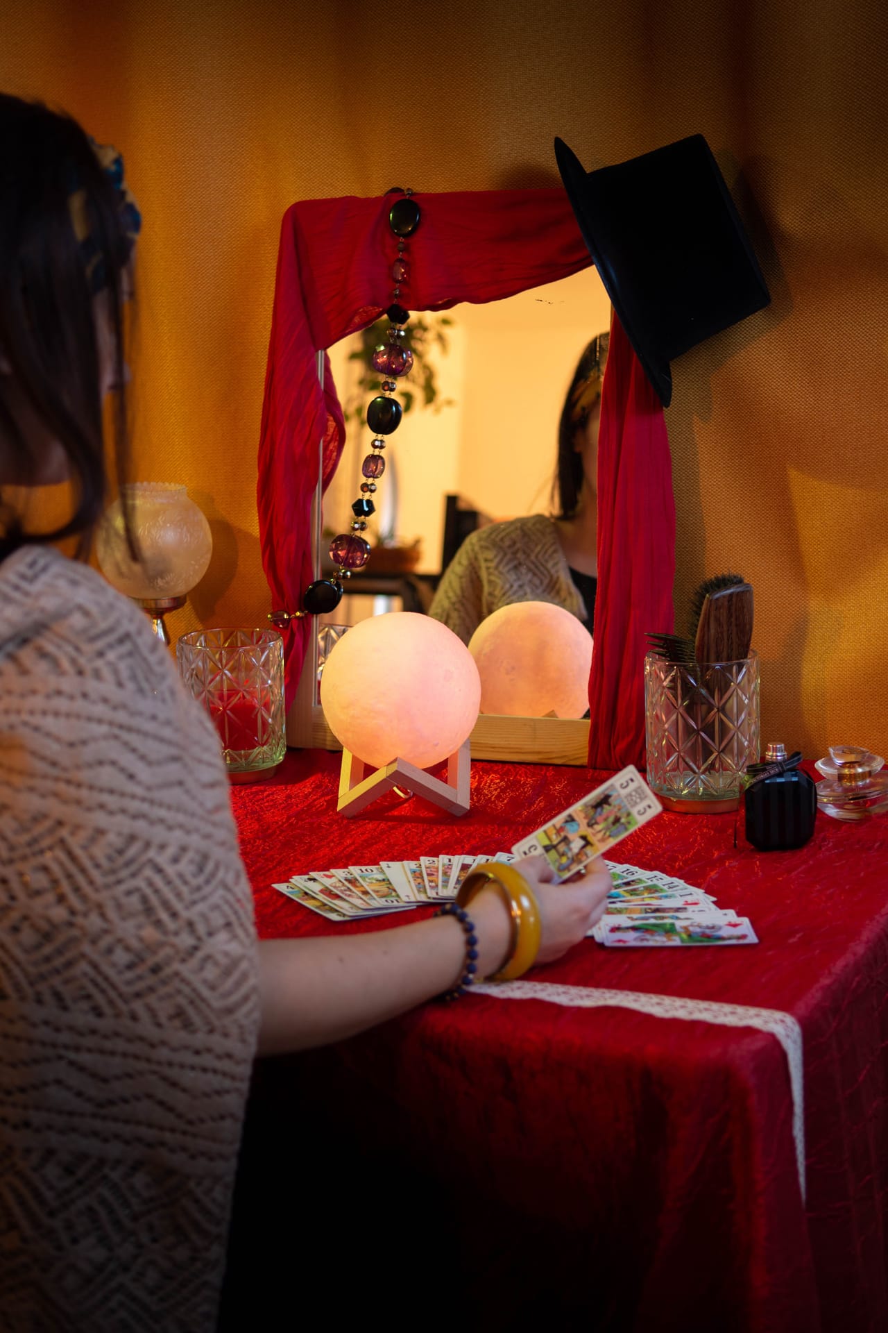 Une joueuse examine des cartes et une boule de cristal dans un décor de cabaret rouge